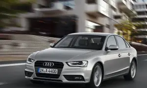 Srebrne Audi A4 B8 pędzi ulicą, rozmywając tło nowoczesnych budynków.