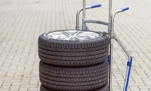Stos czterech opon samochodowych na wózku. Zastanawiasz się, ile waży opona samochodowa? Ten zestaw jest gotowy do transportu.
