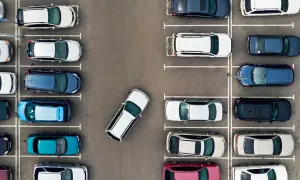 Widok z góry na parking, gdzie samochody zaparkowane są prostopadle. Widać różne kolory i modele aut.