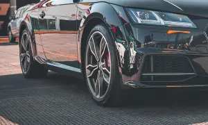 Błyszczące, czarne auto sportowe z felgami i widocznym rantem ochronnym opony.