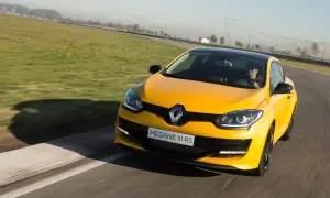 Żółty Megane RS na torze wyścigowym, kierowca w czapce z daszkiem za kierownicą.
