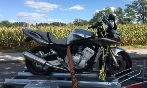 Kupiłem motocykl, co dalej? Srebrny Yamaha Fazer na przyczepce, gotowy na nowe przygody wśród pól kukurydzy.