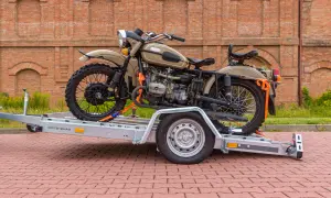 Jak przewieźć motocykl? Na przyczepie MOTO-QUAD, zabezpieczony pasami, gotowy do transportu.