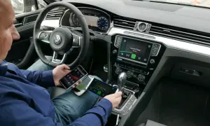 Mężczyzna w samochodzie testuje funkcję mirror link, podłączając trzy telefony do systemu multimedialnego.