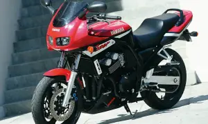 Czerwony motocykl Yamaha Fazer 600 z czarnym siedzeniem i owiewką, zaparkowany na zewnątrz.