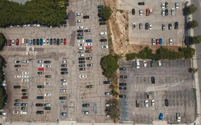 Widok z lotu ptaka na parking, gdzie doszło do kolizji na terenie prywatnym. Widać wiele zaparkowanych samochodów.