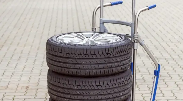 Stos czterech opon samochodowych na wózku. Zastanawiasz się, ile waży opona samochodowa? Ten zestaw jest gotowy do transportu.