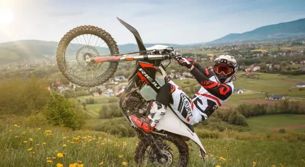 Motocyklista wykonuje jazdę na jednym kole na tle malowniczego krajobrazu. Uważaj, bo taka jazda na jednym kole może skończyć się mandatem!