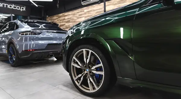 Błyszczące, zielone BMW i szare Porsche w studio auto detailing. Perfekcyjne wykończenie lakieru.