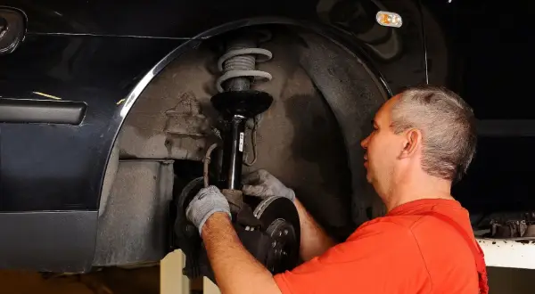 Mechanik naprawia zawieszenie, by auto nie ściągało w lewo podczas jazdy.
