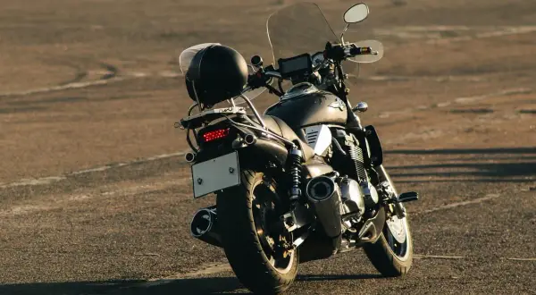 Czarny chopper z chromowanymi elementami i szybą. Kask na bagażniku. Idealny do modyfikacji, jak upiększyć choppera.