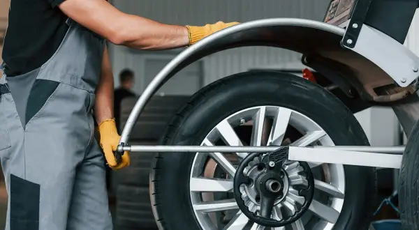 Mechanik w żółtych rękawiczkach dokonuje doważania kół na samochodzie, dbając o płynną jazdę.