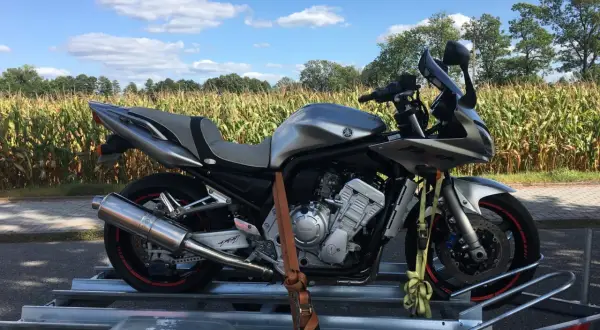 Kupiłem motocykl, co dalej? Srebrny Yamaha Fazer na przyczepce, gotowy na nowe przygody wśród pól kukurydzy.