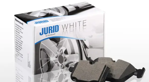 Dwa klocki hamulcowe Jurid White, wykonane z materiałów ceramicznych, leżą obok pudełka z tymi samymi klockami.