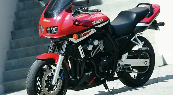 Czerwony motocykl Yamaha Fazer 600 z czarnym siedzeniem i owiewką, zaparkowany na zewnątrz.
