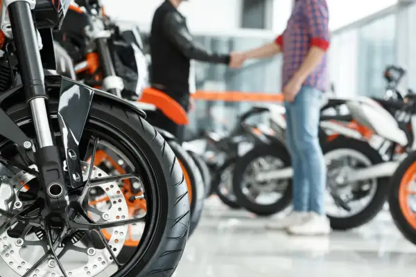 Zbliżenie na koło motocykla pcc-3 wzór. W tle dwóch mężczyzn ściska sobie dłonie na tle innych motocykli.
